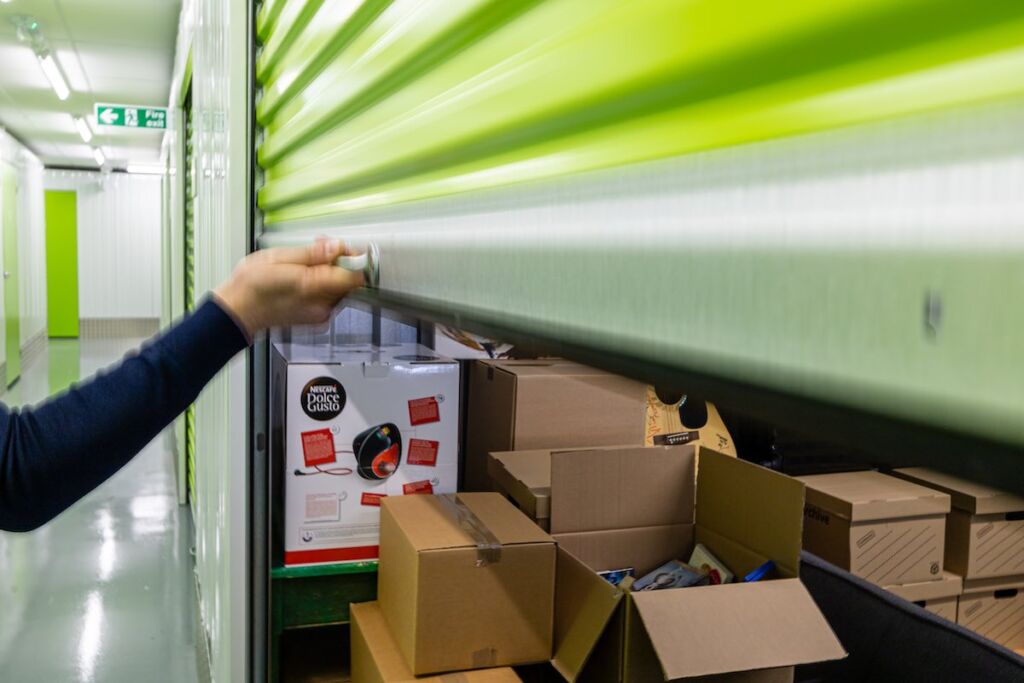 View of a hand pulling down the shutter of a self-storage unit at Clear Space Self-Storage Centre.